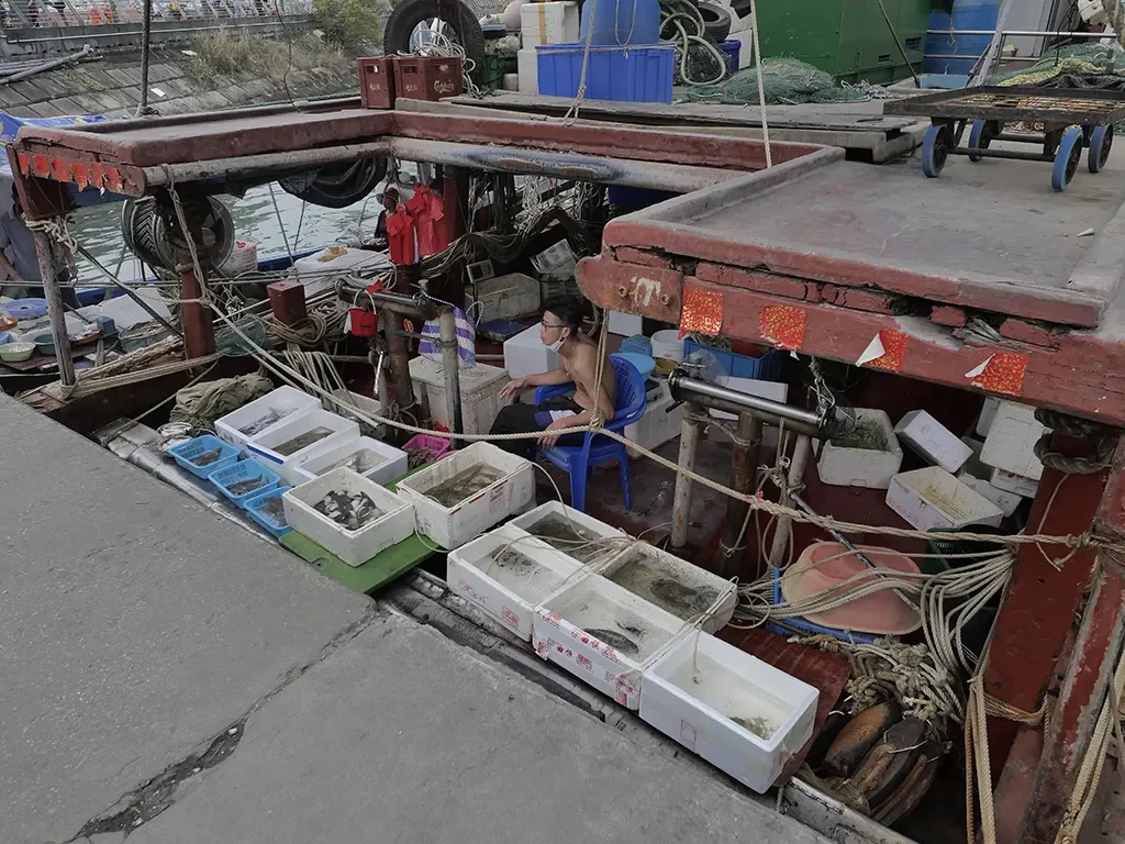 A fisherman selling seafood right on the boat.