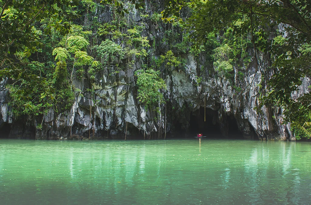 Puerto Princesa Subterranean River National Park Palawan Philippines with limestone cave entrance, green river water, and dense tropical forest.