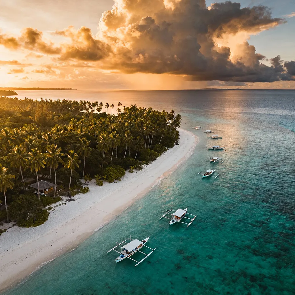 Aerial view of a hidden tropical island in the Philippines surrounded by turquoise water and palm trees.